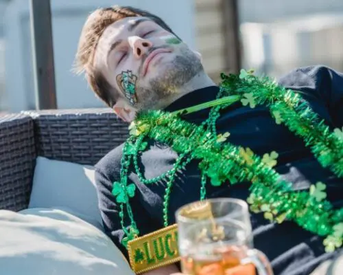 man passed out holding a beer covered in shamrocks