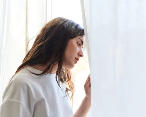 Sad young woman crying in her bedroom at home. Mental health concept.