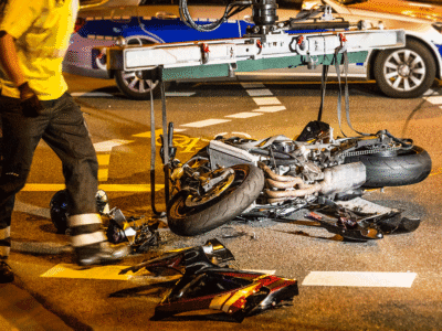 A mangled motorcycle laying on the street after a crash.