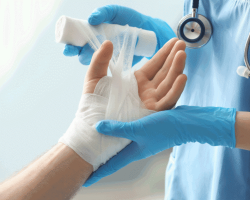 A medical professional with gloves wraps a hand in gauze.