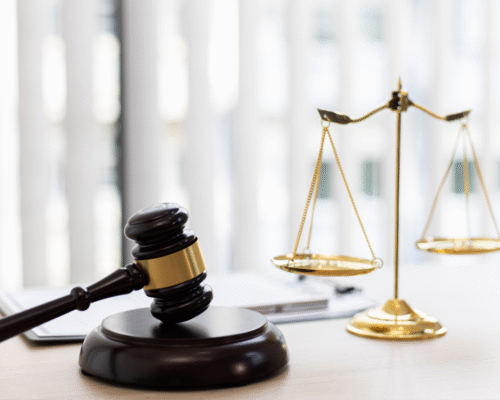 A judges gavel and gold scale of justice on the desk.