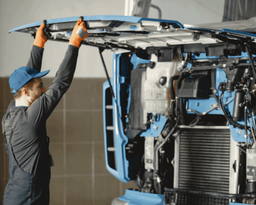 A mechanic looking under the hood of a big rig truck.