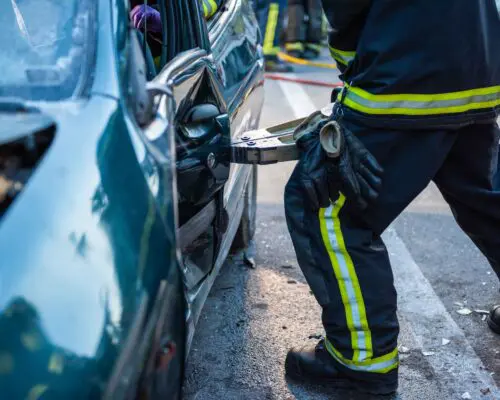 Shot of a firefighter opening door with clamp to rescue a driver from a damaged car.