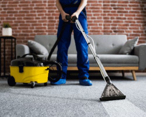 A man in work clothes professionally cleaning carpets with a machine.