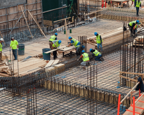 Construction crew working on steel reinforcement and wooden framing for a commercial building project