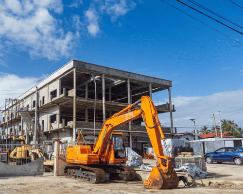Excavator parked at an active construction site with a partially built concrete structure in the background