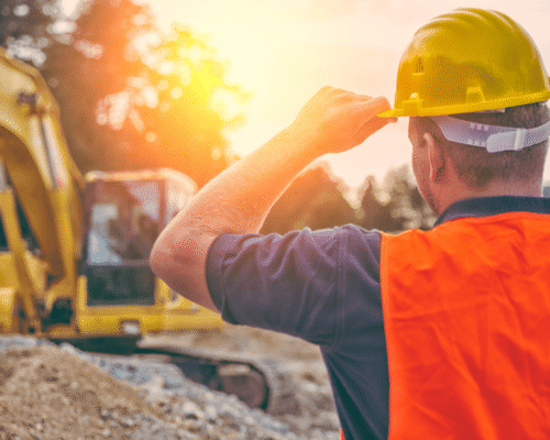 A construction worker in a safety vest and hard hat standing in front of an excavator, symbolizing a NYCHA construction injury lawsuit.