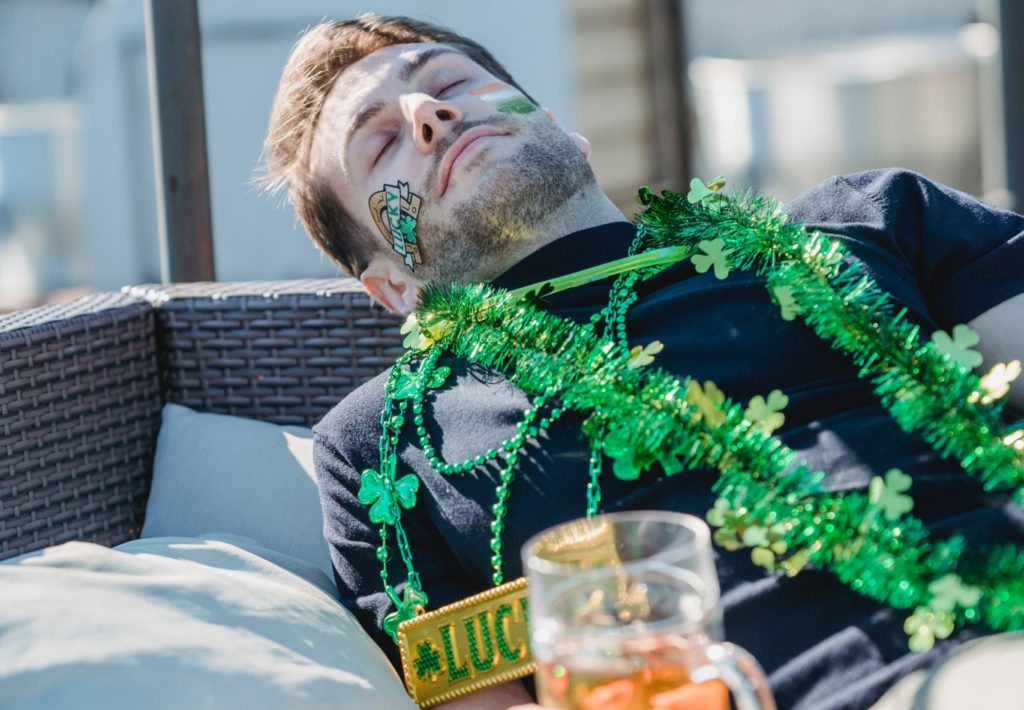 man passed out holding a beer covered in shamrocks