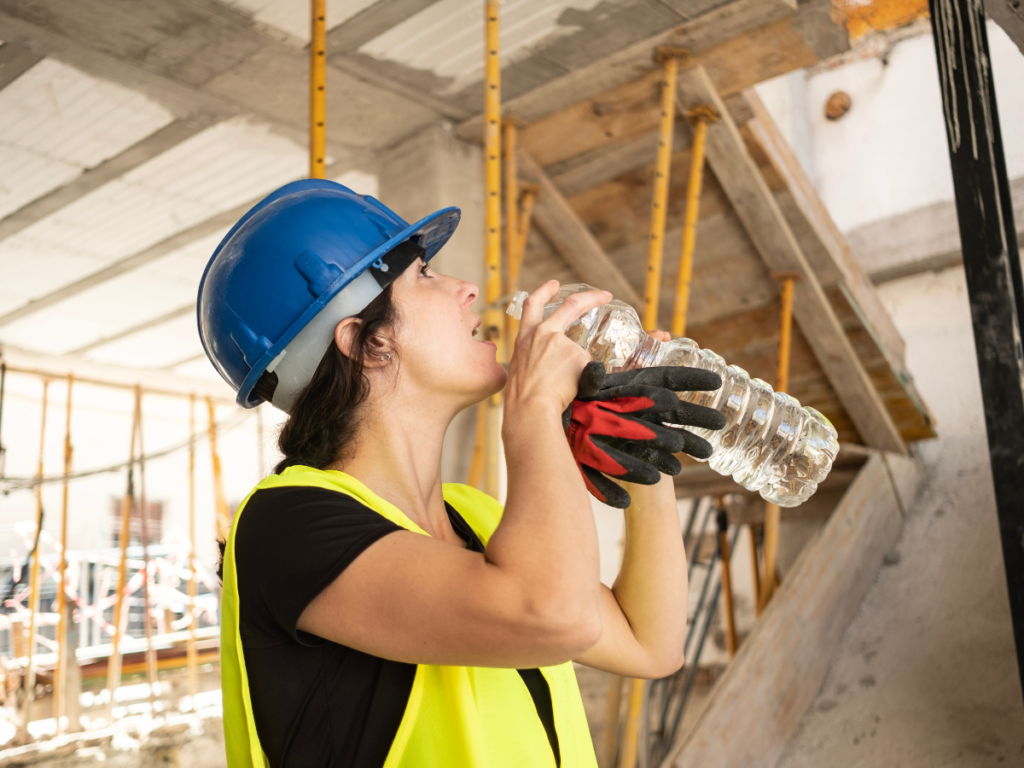 Construction worker drinks water from a water bottle.