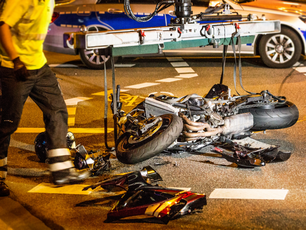 A mangled motorcycle laying on the street after a crash.