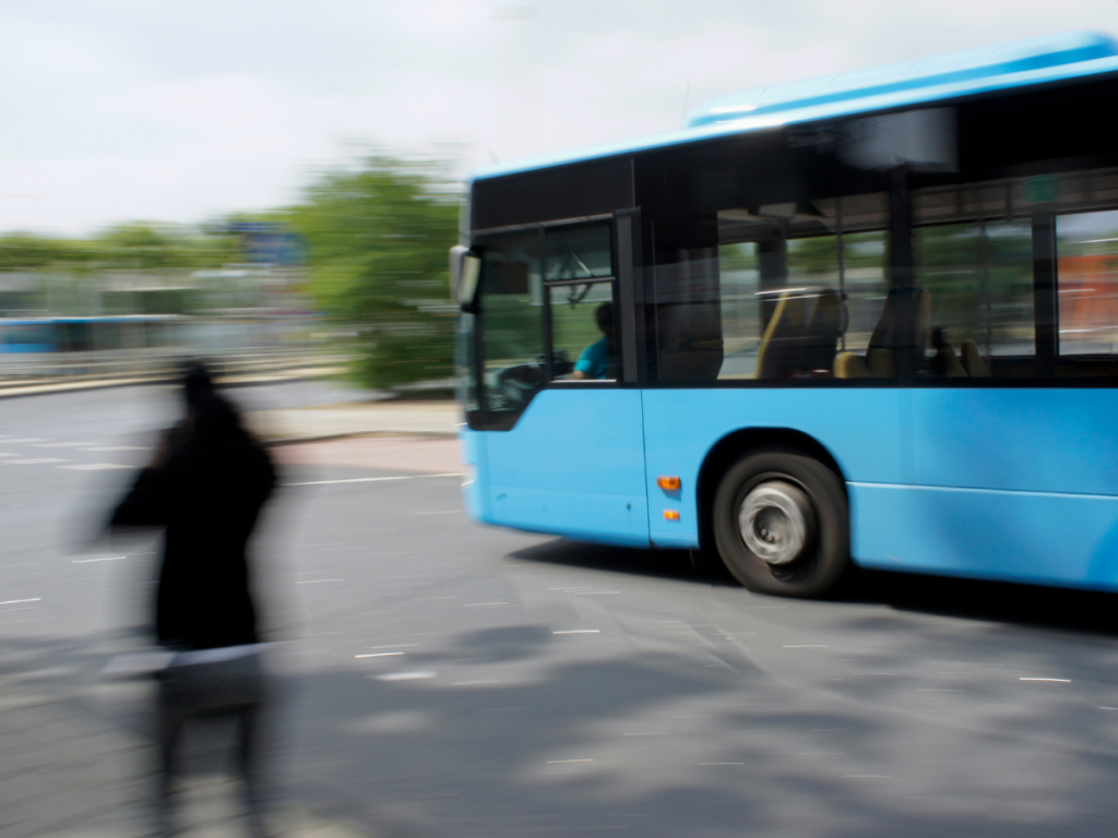 A blue city bus and a pedestrian moving in a blur.